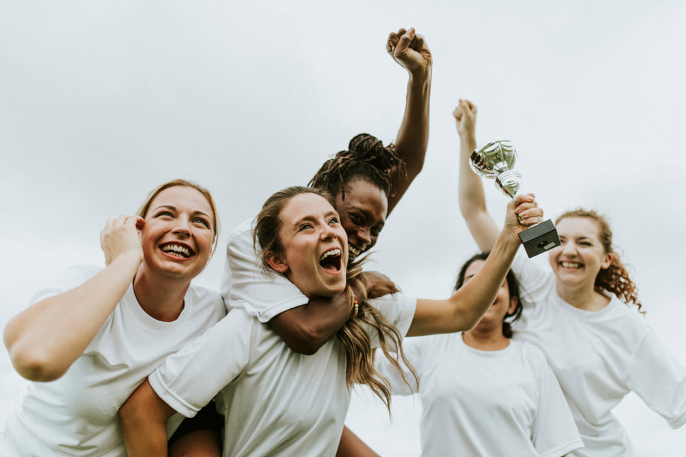 Female athletes celebrating together with a trophy